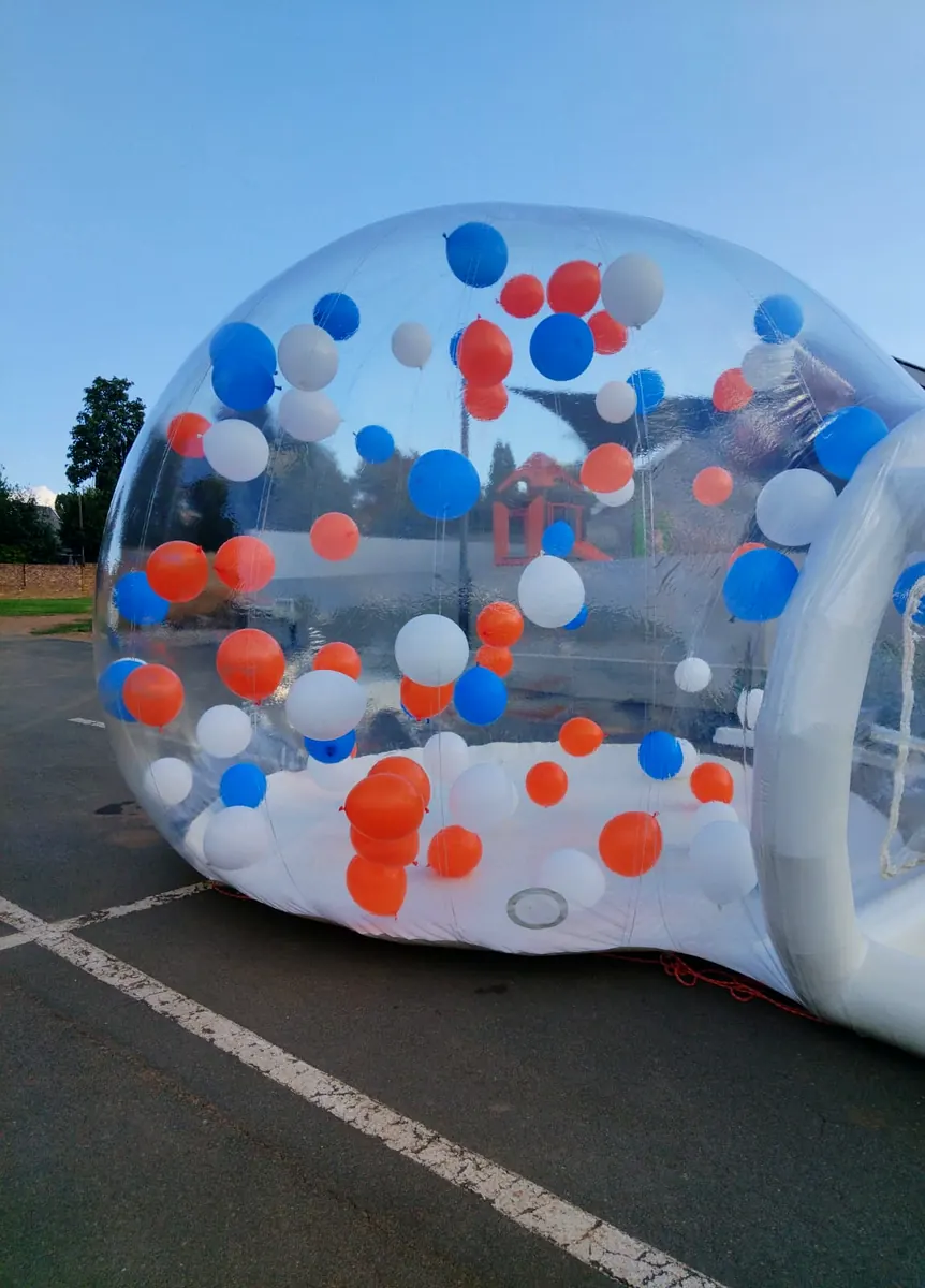 Bubble dome full of orange, blue and white balloons at dusk