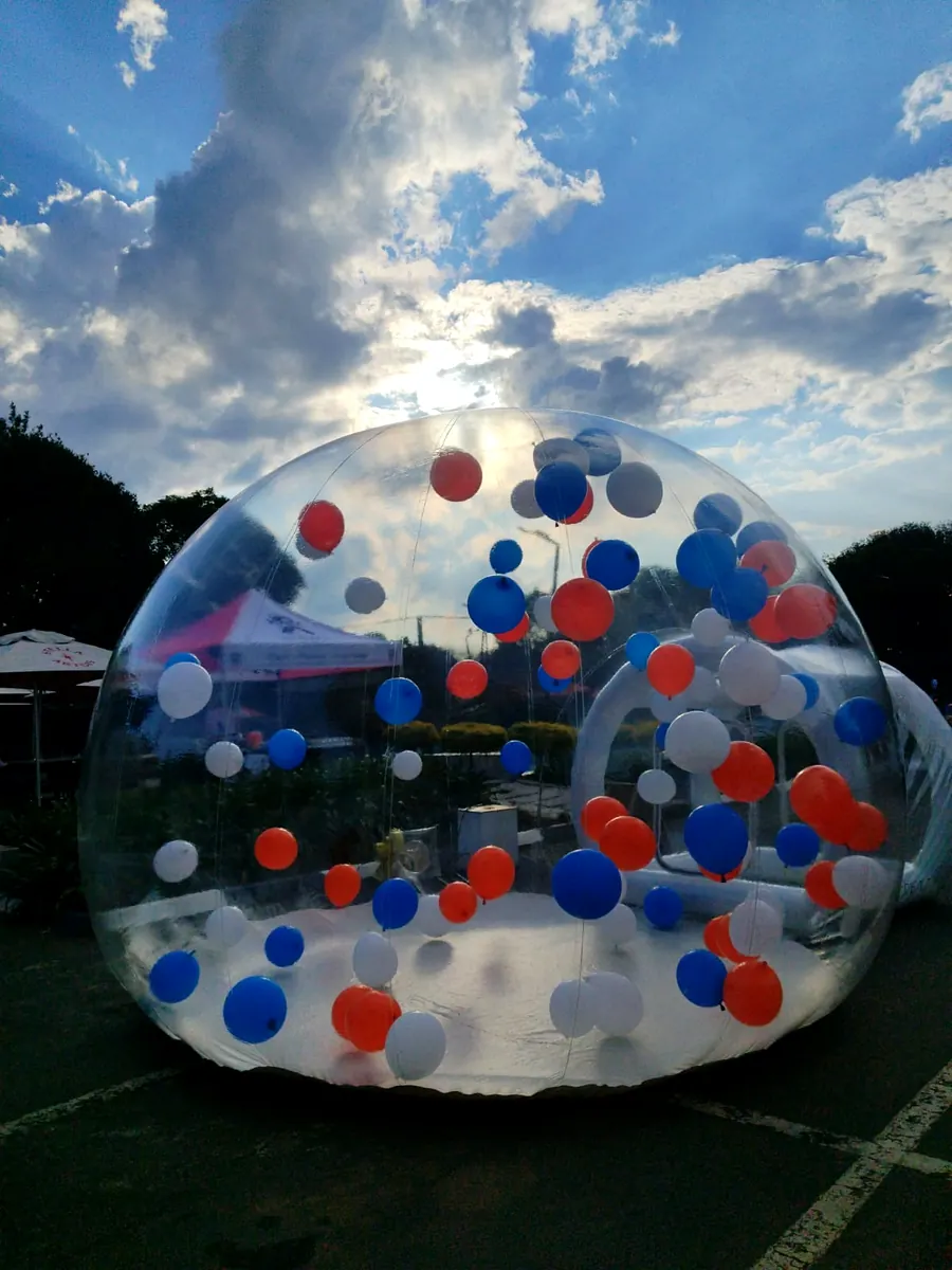 Bubble dome with red, white and blue balloons under a dramatic cloudy sky