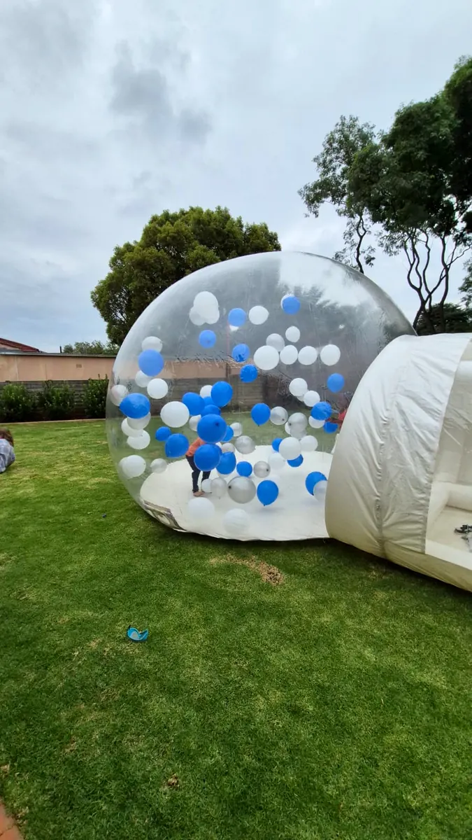 Bubble dome with blue and white balloons on a green lawn