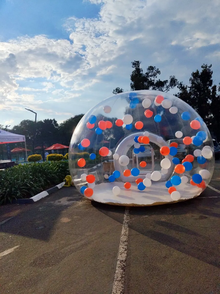 Bubble house with orange, blue and white balloons set up for an evening event
