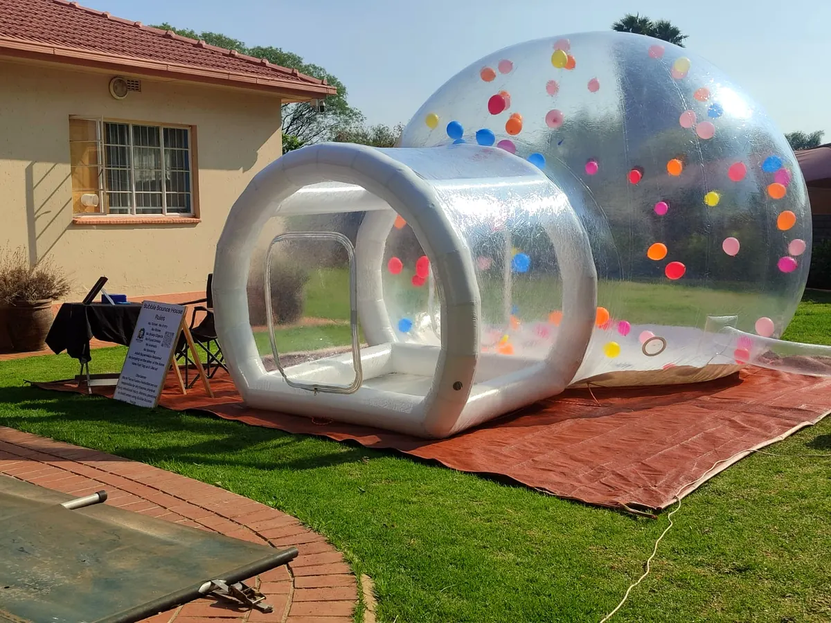 Bubble bounce house on a lawn in front of a red-roofed house