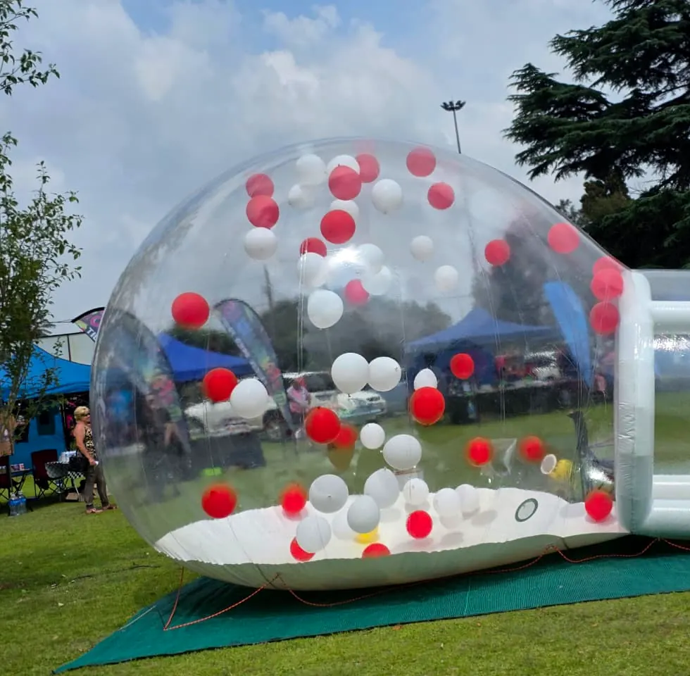 Bubble dome with red and white balloons at an outdoor fun day