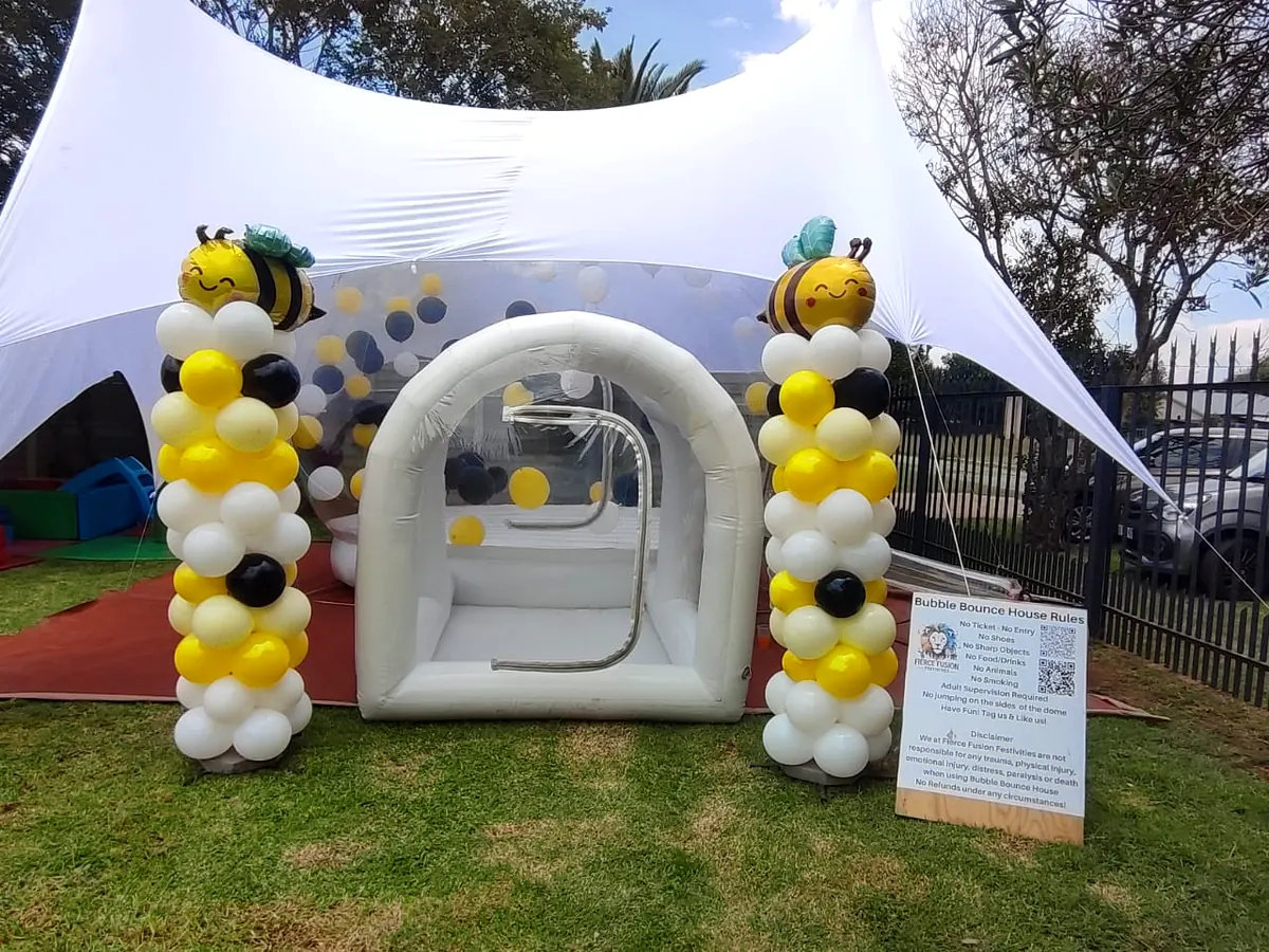 Bumblebee-themed balloon pillars at a bubble house entrance under a stretch tent